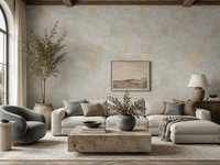 A styled living room featuring a textured, warm beige and gray plaster-style wall mural as the focal point, decorated with a landscape painting, a light gray sectional sofa, a blue-gray accent chair, and a stone coffee table.