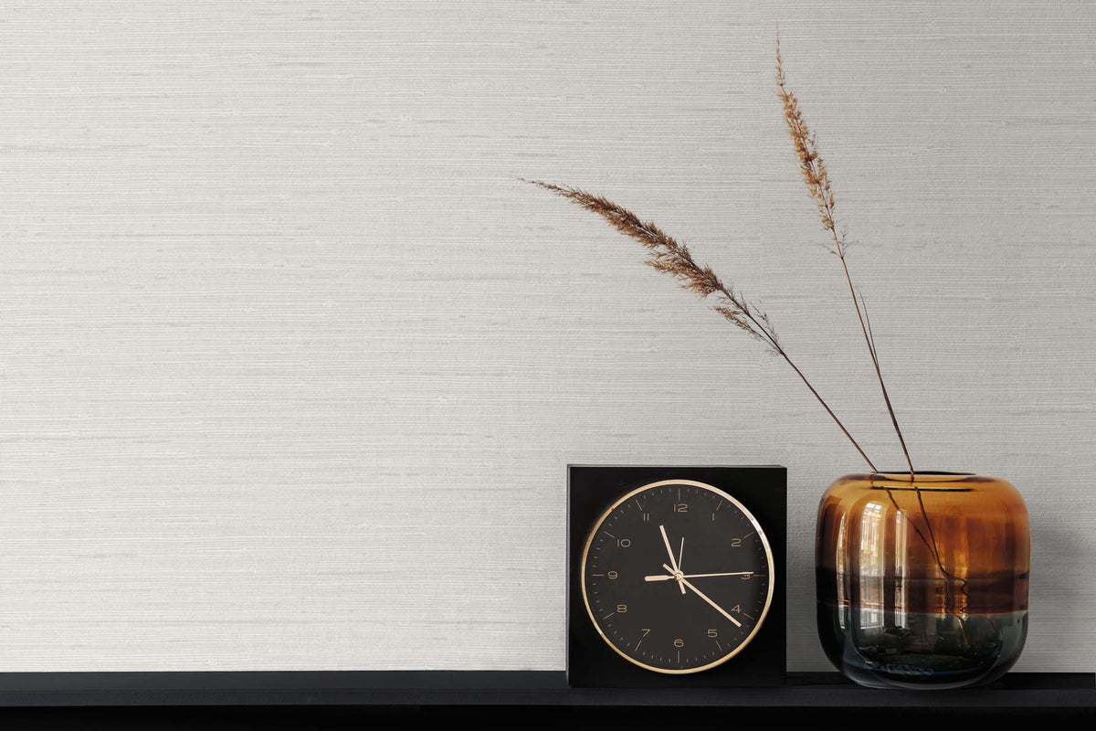 Vinyl off white textured wallpaper with a black and gold clock, and a bronze ombre vase with wheat leaves