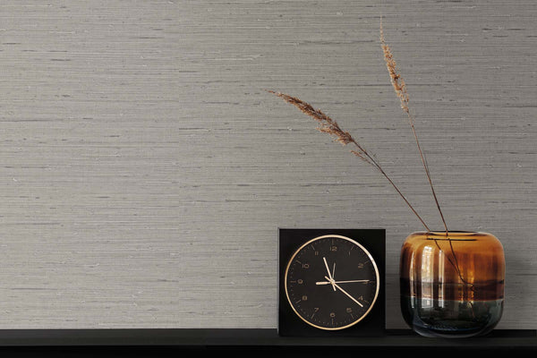 grey matte grasscloth wallpaper with a black and gold clock, burnished vase, two strands of wheat